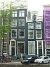 Pand met gevel onder rijk gesneden lijst en attiek met deur en omlijsting uit dezelfde tijd, doch neo-louis XV/empire snijraam