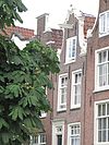 Huis met gave ingezwenkte halsgevel waarin deuromlijsting met deur en snijraam