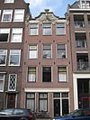 Huis waarvan de gevel wordt bekroond door een gebeeldhouwde zandstenen lijst, van elders afkomstig