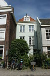 Achter een voorerf liggend huis onder schilddak, met gepleisterde gevels