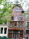Huis met gevel in middeleeuwse trant maar met neo-renaissance details, opmerkelijke houten pui, van de gangbare afwijkende kleuren