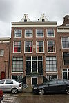 Twee een complex beneden- en bovenwoningen vormende panden met gevel onder rechte lijst waarboven loden dakafsluitingen