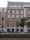 Pand met vier vensters brede gevel met hoeklisenen en lijst waarop balustrade