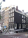 Goed bewaard hoekhuis met voorgevel onder getoogde gebeeldhouwde lijstvormige stenen top