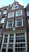 Huis met op de originele bolle puibalk overgebouwde gevel onder klokvormige top met rollagen