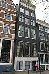 Pand met gevel onder in het midden verhoogde lijst met consoles waarboven een gesneden opzetstuk met onttuigd schip