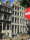 Pand met zandstenen gevel onder gezwenkte gebeeldhouwde top, waarop een borstbeeld
