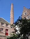 WLM - Minke Wagenaar - 09-07-01 Pakhuis met schoorsteen - In 1879 gebouwd pakhuis in oorsprong gebruikt als opslagruimte met op de begane grond de turbines bestemd voor de gaslampen in de Wintertuin. In 1883 werd het gebouw aan de oostzijde vergroot om onderdak te bieden aan de electriciteitscentrale, de eerste van Amsterdam, die zowel het hotel als het gehele gebied rondom de Dam van electriciteit voorzag. Vermoedelijk was G.B. Salm de architect hiervan. Omschrijving Op een rechthoekige plattegrond in baksteen opgetrokken pakhuis onderdeel van het co…
