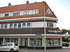 Blok met winkels met brede luifel en daarboven woningen, bouwstijl Amsterdamse School, onderdeel van het centrale achthoekige plein van Tuindorp Nieuwendam