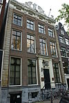 Pand met vierraamsgevel onder rechte gesneden lijst met rijke verhoging en balustrades waarin empire deur