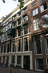 Pand met gevel onder rechte lijst met vensteromlijstingen en gelaagde onderpui voor een ouder huis