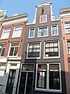 Pand met halsgevel van het 'doorboorde-bloem-type' met een wapenschild in de afdekking