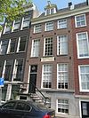 Huis, onderdeel van oud huizenblok met doorlopend dwars dak. Gevel onder rechte lijst. Deur en snijraam met lantaren