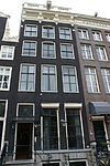 Pand met gevel onder gesneden rechte lijst en balustrade met rijk gesneden deurpartij