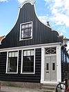 Houten huis met klokgevel (uit- en ingezwenkt voorschot), onderpui in empirestijl
