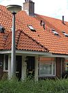 Blok met 8 woningen, gecombineerde toegangen van twee woningen onder een ingestoken schilddak, zijkant met houten topgevel, aan oostkant en westkant toegangspoorten tot binnenterrein, onderdeel van complex bejaardenwoningen in Tuindorp Nieuwendam