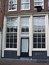 Hoekhuis met klokgevel, houten pui en pothuis tegen de zijgevel