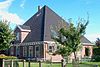 Stolphoeve met dwarseind en bijschuur. Klokvormig houten voorschot met doorbroken fronton en siervazen; gesneden pronkdeur en bovenlicht