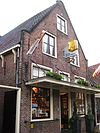 Huis met zadeldak. Houtskelet. Herstelde puntgevel van baksteen