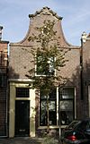 Pand met wat lagere bakstenen halsgevel met bakstenen klauwstukken