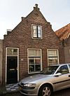 Laag pand met toppilaster en topgevel onder zadeldak