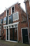 Pand met rechte kroonlijst, ontlastingsbogen met blokken versierd boven de vensters, thans pakhuis