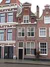 Pand met fraaie klokgevel met pilasters, in midden travee nis met schelp, driehoekig fronton bekroond de gevel, gemetselde rechte afdekkingen boven vensters met uitspringende gemetselde blokken, midden 17