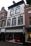 Pand met brede trapgevel in haarlemse trant met natuurstenen blokken in bogen boven ramen en horizontale banden