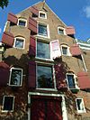 Pakhuis met brede originele ingang met geornamenteerde boog, fraaie trapgevel