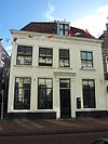 Pand met gepleisterde lijstgevel onder mansarde dak