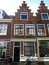 Pand met trapgevel, top rustend op console met leeuwenmasker. Trapgevel gekoppeld aan die van het buurnummer 84