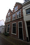 Pand met trapgevel, puntvormige bogen met natuursteenblokken boven de ramen, toppinakel op leeuweconsole rustend