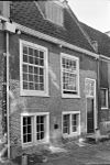 Laag 17e-eeuws huis onder zadeldak met toegespitste bogen boven benedenvensters, souterrain, schuiframen met kleine roeden, rechte gootlijst