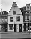 Pand met gepleisterde trapgevel met ontlastingsbogen boven de vensters, midden pinakeltop rustend op console met gebeeldhouwde kop 1e helft 17e eeuw