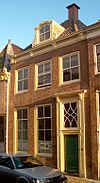 Pand met rechte kroonlijst en dakkapel; schoorsteen boven voorste dakschild. Roeden in de vensters en bovenlicht