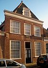 Hoge gevel met drie gevelstenen en roeden in de vensters, voor ouder pand