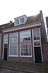 Dubbel dwarshuis onder pannen zadeldak, dat aan de rechterzijde met een dakschild beëindigd is