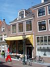 Huis met hoogst eenvoudige gevel, pand wellicht ouder; oorspronkelijk gedetailleerde deuromlijsting. Stoepbanken
