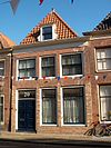 Eenvoudige gevel voor wellicht ouder pand; in de vensters op de verdieping roeden. Pui modern