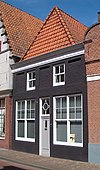 Laag bakstenen pand met rechthoekige spaarvelden op de verdieping