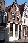 Eenvoudige gevel voor wellicht ouder pand; in de vensters op de verdieping roeden. Pui modern