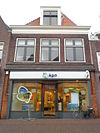 Rechtgesloten eenvoudige gevel met dakkapel voor ouder pand met achtertop waarin kruiskozijn. Pui modern
