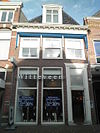 Huis met eenvoudige gevel; omlijste deurpartij met bovenlicht; bescheiden versierde kroonlijst