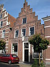 Pand met trapgevel, bogen van dichtgemetselde vensters zichtbaar, gebeeldhouwde steen