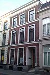 Pand dat onderdeel is van een in het derde kwart van de 19e eeuw als een symmetrisch geheel ontworpen straatwand