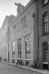 Gesneden voordeur met bovenlicht gevat in een omlijsting, die rococo-ornamenten vertoont