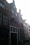 Onderkelderd pand met getrapte tuitgevel, horizontaal geleed door bakstenen tandlijsten
