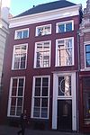 Onderkelderd huis met gepleisterde lijstgevel. Voordeuromlijsting, rococodeur en bovenlicht. Bijzondere geprofileerde natuurstenen omlijstingen van de kelderlichten