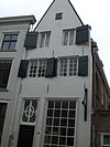 Huis met gepleisterde tuitgevel, afgedekt door eensteens rollaag
