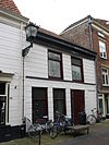 Pand met gepleisterde lijstgevel onder dwars zadeldak